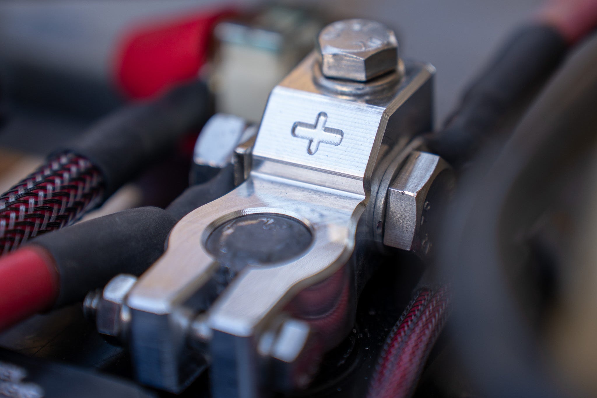 Close-up of a battery terminal with red and black cables in a vehicle setting.